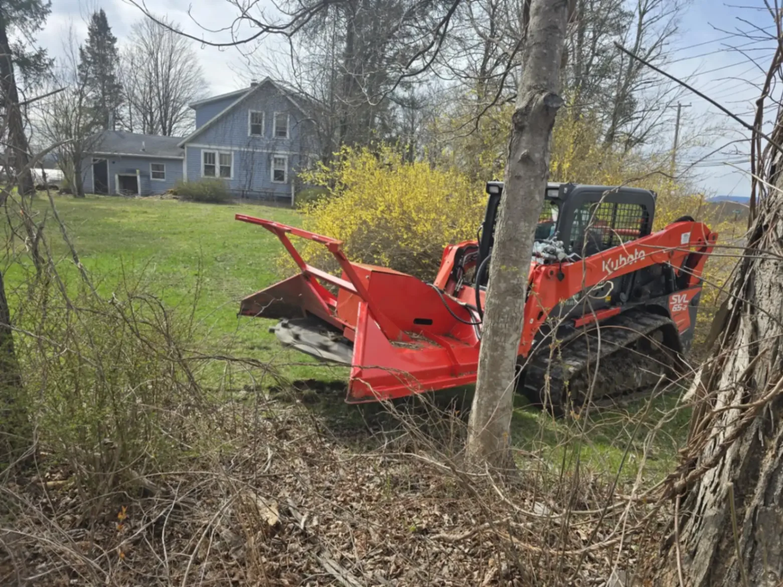 Wood chipper and skid steer equipment in action